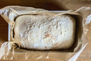 Shaped sourdough loaf in parchment-lined pan before baking
