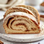Brown Sugar Cinnamon Sourdough Bread: Sweet Swirls & Tangy Crust 3 Close-up of a sliced brown sugar cinnamon sourdough bread swirl with powdered sugar on a white plate