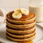 Fluffy Protein Sourdough Pancakes: A Deliciously Energizing Breakfast 3 Stack of protein sourdough pancakes topped with banana slices and drizzled with syrup
