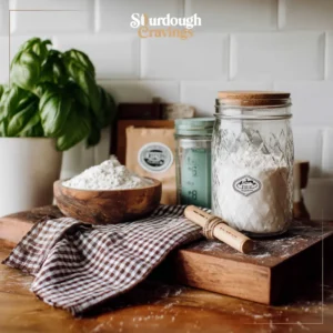 what is sourdough discard? A labeled glass jar of sourdough discard on a vintage wooden board, white subway tile backdrop with blurred basil, warm light.